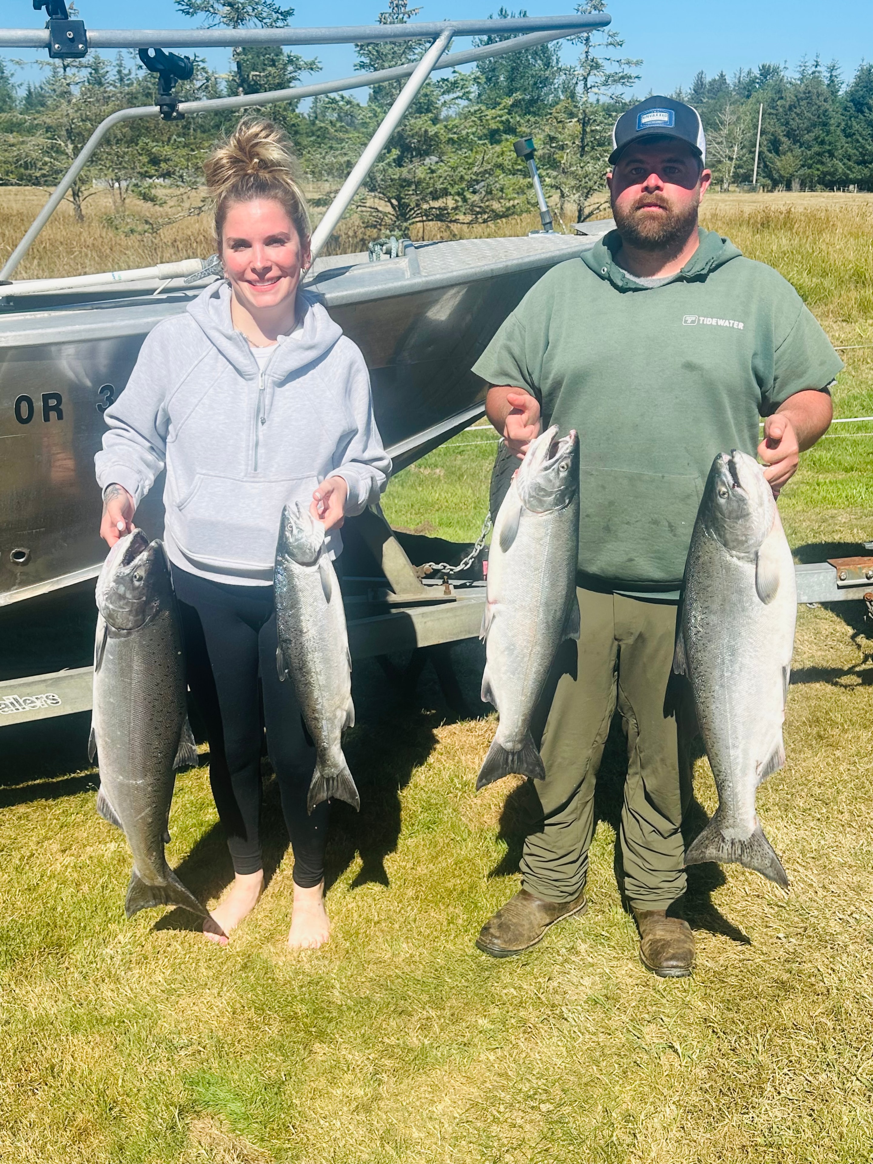 Couple holding a limit of Chinook salmon next to the boat